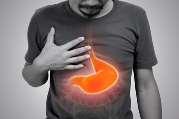 Asian man suffering from gastritis on gray background.
