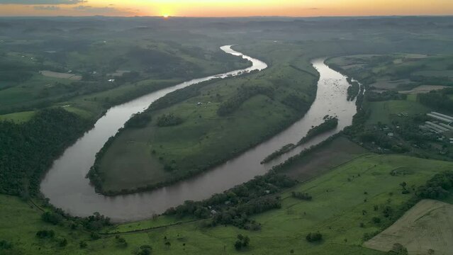 Aerial view of winding river at sunset amid green fields and forest. Volta do Dedo. Chapec&oacute; river. 4K.