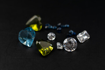 Colorful faceted gemstones on black background, heart shaped crystal gems