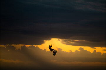 kite surfer siluete flying into a storm in a sunset