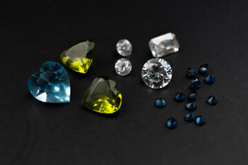 Colorful faceted gemstones on black background, heart shaped crystal gems
