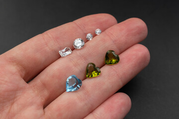 Colorful faceted gemstones on black background, heart shaped crystal gems