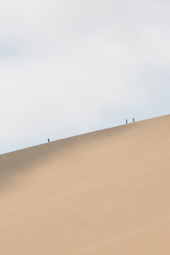 Minimal desert photography. People are walking on the mountain desert. Desert and sky minimal photograghy concept. Open space area.