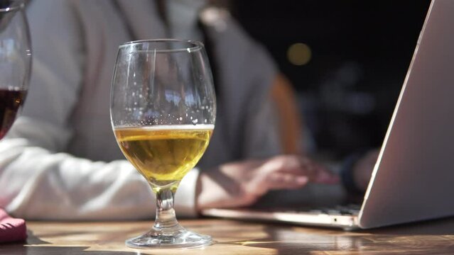 A woman with a glass of beer works at the computer