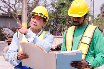 Fototapeta premium Male engineer in safety helmet inspecting construction drawings at construction site building construction concept.