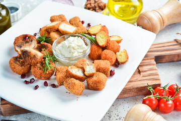 Fondue. Fondue with cheese, mushrooms and vegetables. On a white plate. On a gray stone background. Restaurant menu.