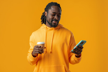 Portrait of handsome african man using his mobile against yellow background