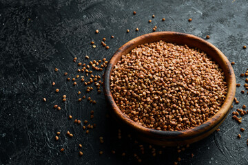 Organic buckwheat groats in a wooden bowl. on a stone background. Healthy food.