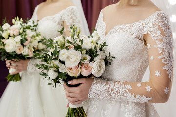 the bride in a white wedding dress holds her wedding bouquet in her hands