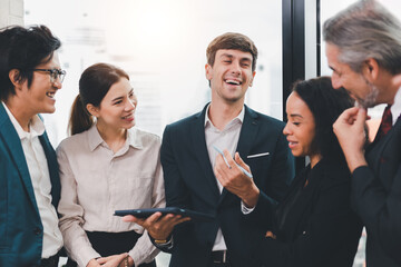 A team of exclusive diversity businesspeople are gathered together in an office, excitedly watching...