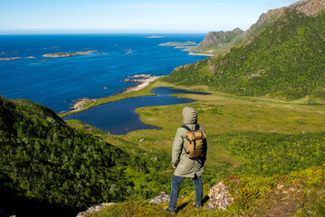 Fototapeta na wymiar A man enjoy the scenic nature. Northern beauty panoramic view. Fjord, ocean and mountain landscape. Travel, adventure. Sense of freedom, relax lifestyle. Explore North Norway. Summer in Scandinavia