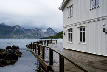 Norwegian house on the background of mountains. Tourist attraction in Norway. Amazing scenic outdoor view. Travel, adventure, relaxed lifestyle. Lofoten Islands