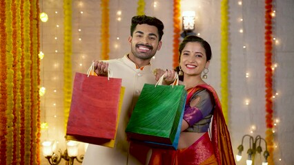 Happy young couple with shopping bags in hand looking camera - concept of festival offers, promotional sales and discount