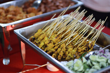 Skewered and grilled meat, Malaysian satay served on warm trays during party. Asian buffet style delicacies.