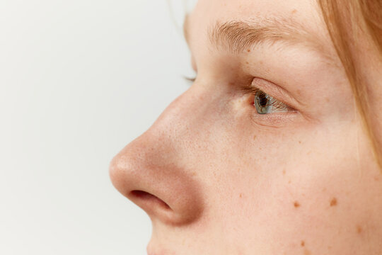 Side view close-up image of male face, eyes and nose. Young redhead model posing over grey studio background. Concept of men's health, body and skin care, hygiene and male cosmetology