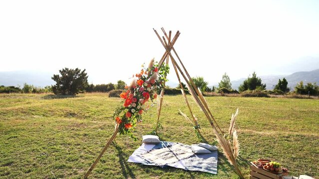 Wedding arch in the form of an Indian wigwam stands on a green meadow