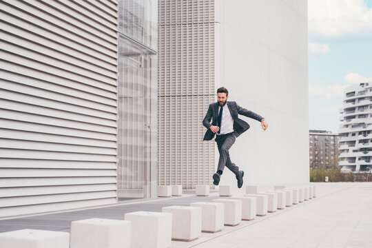 Energetic young bearded professional businessman jumping in mid-air