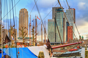 Fototapeta na wymiar Cityscape of Rotterdam - view of the Tower blocks in the Kop van Zuid neighbourhood through the rigging of the moored sailboat, South Holland, The Netherlands
