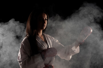 beautiful girl exercising karate pose against fog background