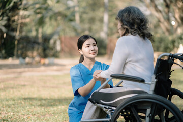 Obraz premium Young nurse holding hands of senior woman in wheelchair.