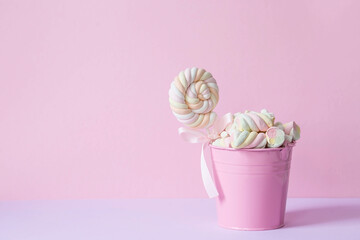 Marshmallows. Chewing candy close-up on a pink background. Dessert of sweet dishes in a pink bucket. Pastel colors. A copy of the text space.