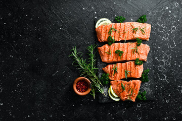 Grilled trout fillet with spices, lemon and vegetables. On a black background.