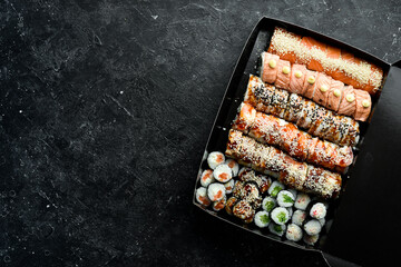 Set of sushi and rolls. Chinese food set. Takeout, food delivery. On a black stone background. Top view.