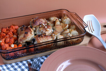 One-dish meal hot from the oven: chicken thighs, potatoes, and carrots, topped with diced onions.