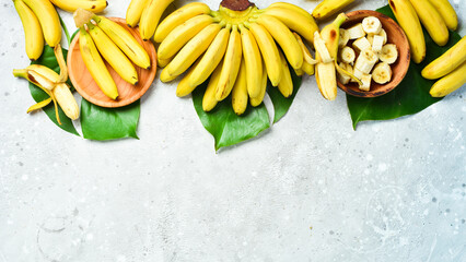 A bunch of bananas and a sliced banana baby on a table, delicious, natural. On a stone background....