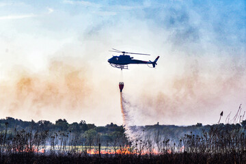 helicopter flying over a fire, helicopter putting out fire, helicopter with bambi bucket
