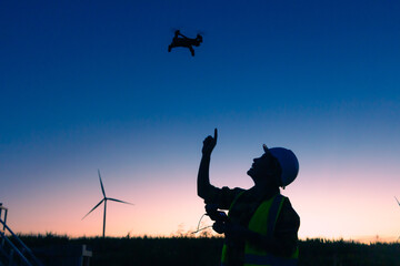 asian female engineer using drone for  inspection wind turbine farm in evening.