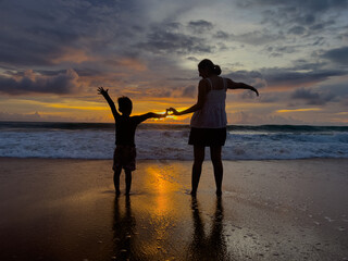 Fototapeta premium Mother and daughter take a walk on the beach in the evening.