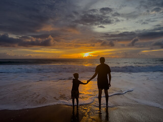 Father and son sitting on the beach in the evening