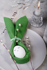 Easter funny Bunny egg made of green napkin, Easter table decoration with willow tree branches.