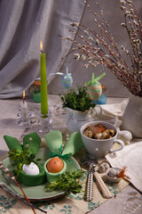 Festive Easter table setting with napkin Easter Bunny, fresh organic greenery, willow tree branches and easter eggs.