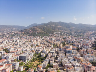 Fototapeta na wymiar Top view of the tourist city of Alanya in Turkey, low-rise buildings of the city from above against the backdrop of mountains, on a sunny summer day