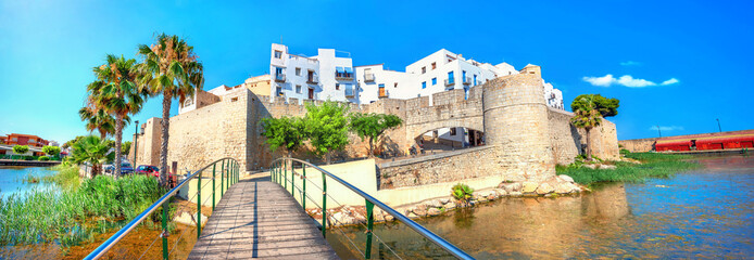 Panoramic landscape with pedestrian bridge and view of fortress walls and buildings in Peniscola town. Spain