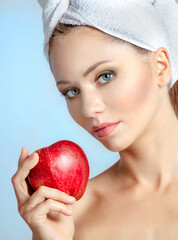 Portrait of attractive young woman in towel on head with red apple