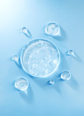 round drops of transparent gel serum on blue background