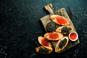 Sandwiches with caviar and butter. Caviar in a bowl. Premium snacks. On a stone background. top view
