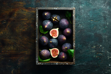 Figs and leaves on a dark stone table. On a dark background. Space for text. Top view.