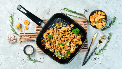 Cooked chanterelle mushrooms with onions and spices in a pan on the kitchen table. Top view. Free space for text. © Yaruniv-Studio