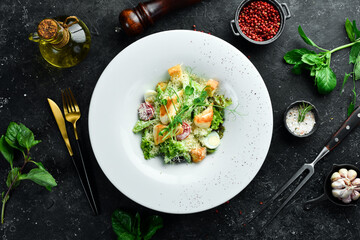 Traditional Caesar salad with chicken. On a black stone background.
