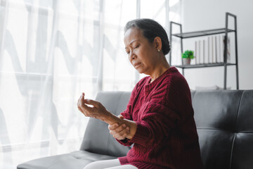 Elderly asian housewife woman sitting on sofa. wrist pain