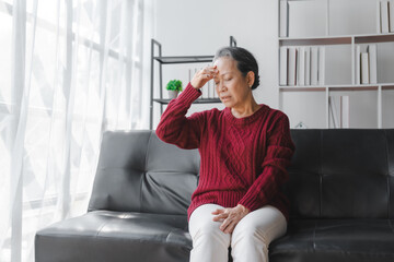 Elderly asian housewife woman sitting on sofa. depression