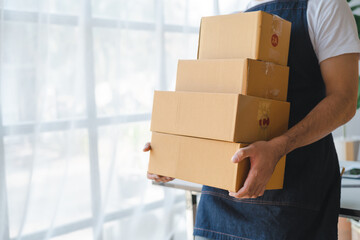 Young asian sme business man in apron working at warehouse home office freelancer retail logistic company with package box checking customer address.