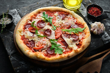Homemade pizza: sausages, bacon and tomatoes. Takeaway food. Home delivery of food. On a black stone background.