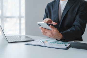 Fototapeta premium Young handsome asia business man in formal suit working with monthly report balance sheet and yearly tax of accounting to verify the account by an authorized auditor