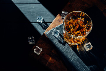 A glass of whiskey on a wooden table. In a glass filled with alcohol from the bottle.