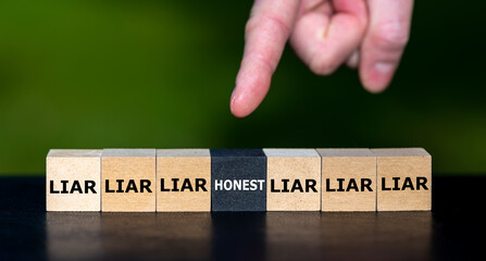Hand selects the cube with the word 'honest' instead of cubes with the word 'liar'.